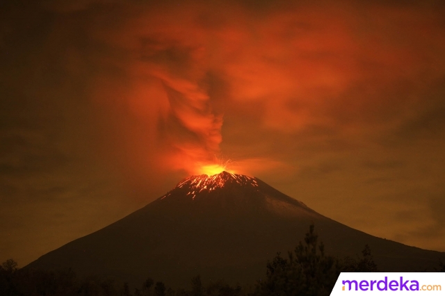 Penampakan langit malam yang memerah ketika lava pijar, abu, dan asap terlontar dari kawah Gunung Popocatepetl sebagaimana terlihat dari wilayah Santiago Xalitzintla, Puebla, Meksiko, pada 22 Mei 2023.