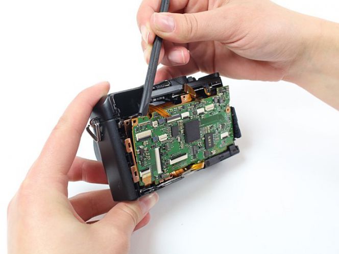 Setelah EVF tak lagi berada di tempatnya, barulah Anda bisa mengeluarkan motherboard dari body kamera. Lakukan dengan perlahan agar tak membuat komponen-komponen kecil di dalamnya rusak.