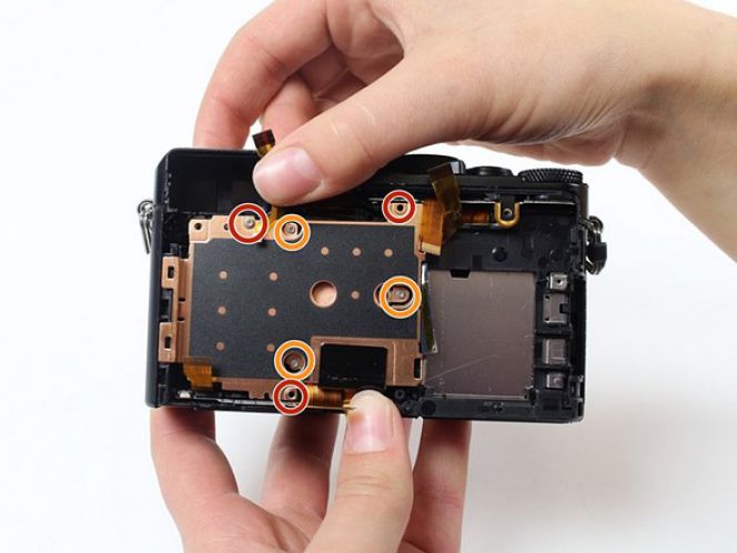 Di balik motherboard, tampaklah sebuah plat tembaga. Perhatikan lebih teliti, dan jangan sampai ada sekrup tertinggal saat hendak melepas bagian ini.
