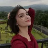 Dinda Annisa berpose dengan latar belakang pemandangan indah.