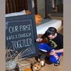 ＂Momen Halloween pertama kita bersama,＂ arti tulisan dalam papan. Siapa yang dimaksud dengan 'kita'?