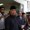 Ahmad Dhani tersenyum kepada wartawan