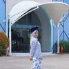 Aisha Keem foto pakai topi toga di depan sekolah