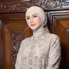 Mulan Jameela berdiri di depan latar belakang kayu