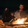 Dylan O'Brien di dekat api unggun dalam film SEND HELP