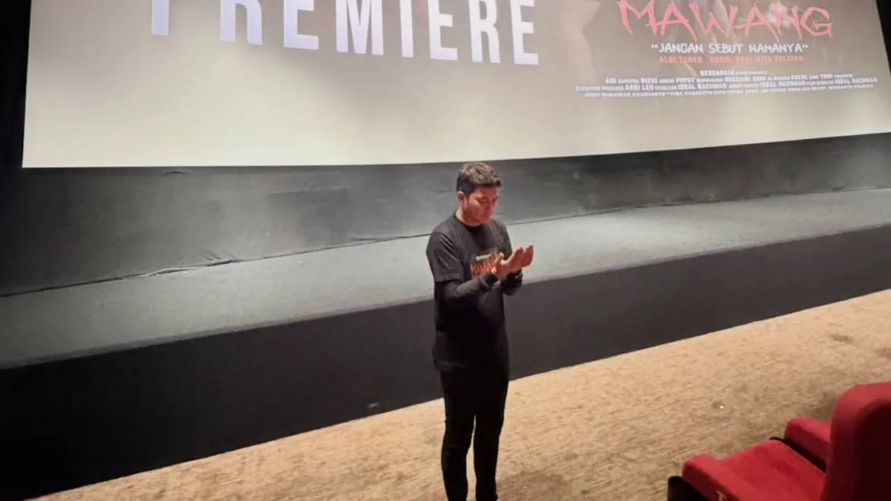 映画『MAWANG JANGAN SEBUT NAMANYA』のロゴが映るスクリーンの前で手を合わせるアルディ・タヘル