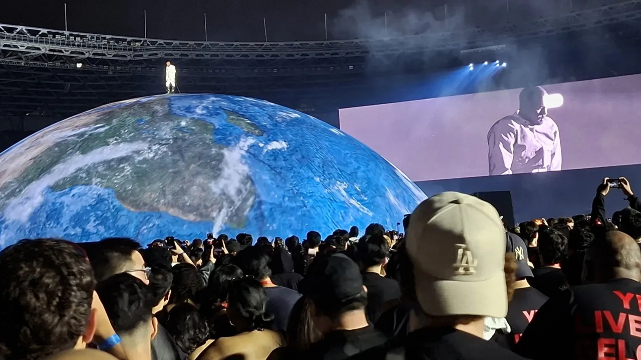 ジャカルタ公演で地球を模した球形ステージ上に立つYeと、客席の観客