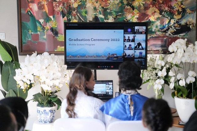 Menghadiri wisuda yang digelar secara online, Rizky Langit Ramadhan menggunakan perangkat laptop yang disambungkan ke layar televisi.