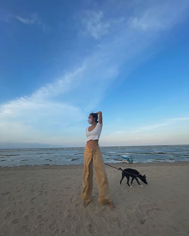 Kamu juga bisa menemukan potret Eva saat memakai crop top saat mengajak anjingnya jalan-jalan ke area pantai.