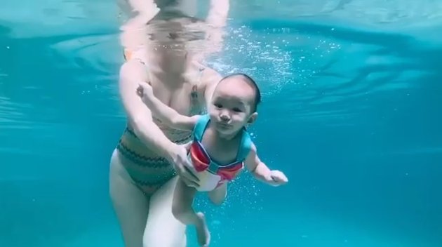 Meski masih bayi, sepertinya baby Claire sudah terbiasa berenang atau menyelam. Lihat saja ekspresinya saat menahan napas ini. Gemesin kan. 