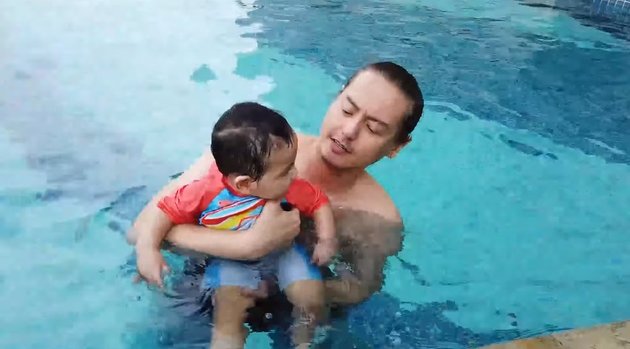 Bersama sang papa, bayi yang sebentar lagi genap berusia 1 tahun ini tampaknya senang banget berenang.