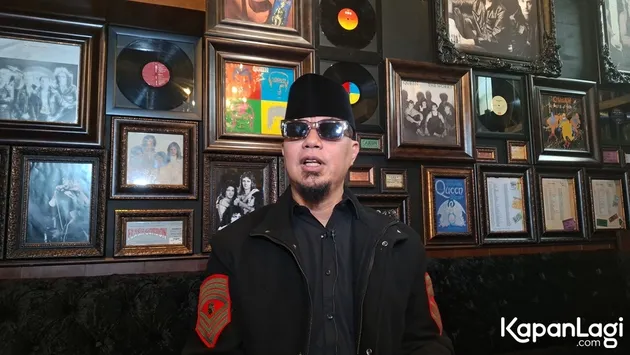 Ahmad Dhani duduk di depan dinding penuh pigura