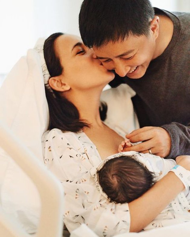 Celina Jade membagikan momen bahagianya mencium sang suami tercinta sambil menggendong bayi perempuan mereka yang baru lahir di akun Instagram pribadinya.