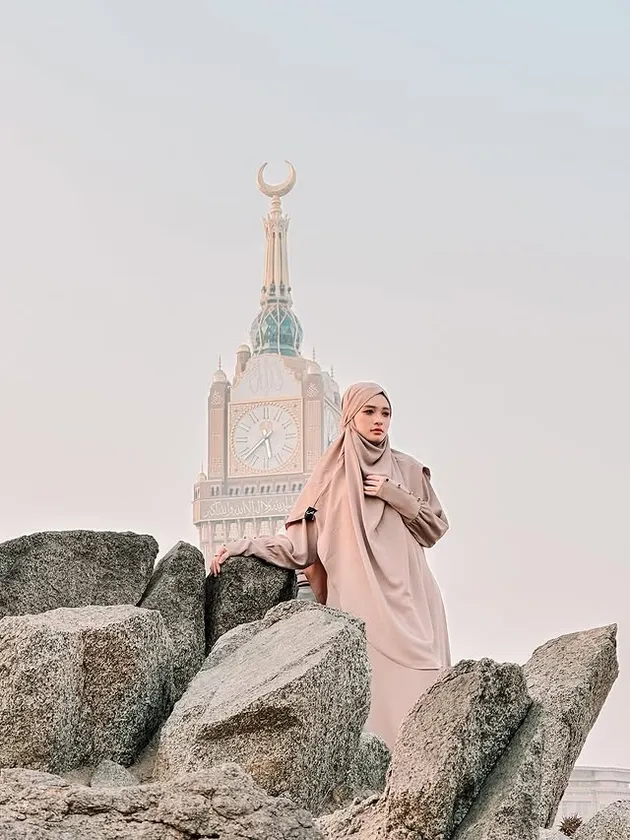 Inara Rusli berdiri dengan latar belakang Masjidil Haram