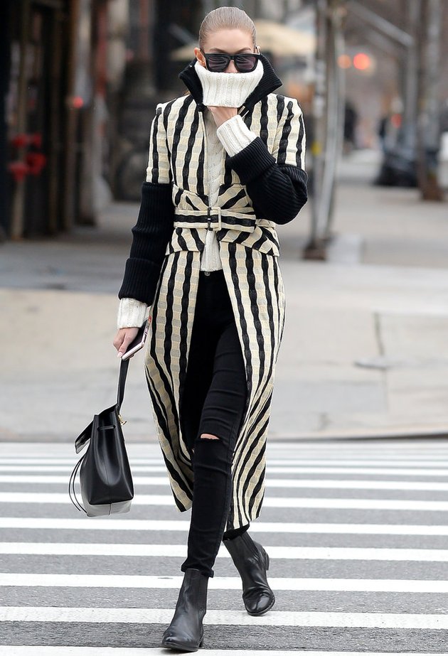 Pertama ada supermodel cantik Gigi Hadid yang terlihat chic dengan coat panjang motif garis-garis yang dia pasangkan dengan knit sweater putih dan jins hitam. Fabulous!