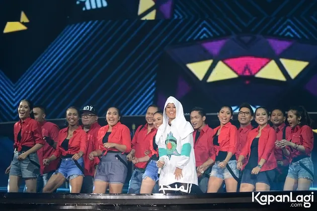 Agnes Monica tampil dalam balutan jaket putih besar dengan backing dancer yang memakai atasan merah serta bawahan jeans.