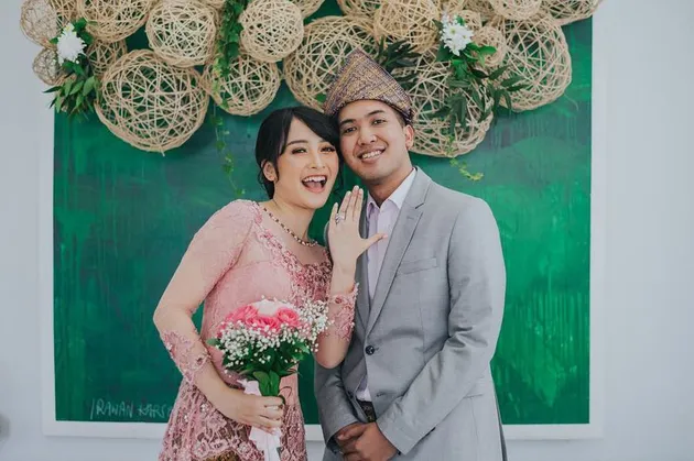 Dengan bangga Kinal menunjukkan cincin pertunangannya sambil memegang buket bunga Mawar merah jambu yang senada dengan pakaiannya. Sedangkan sang tunangan memakai hiasan kepala ala Sumatera Selatan dan tersenyum riang.