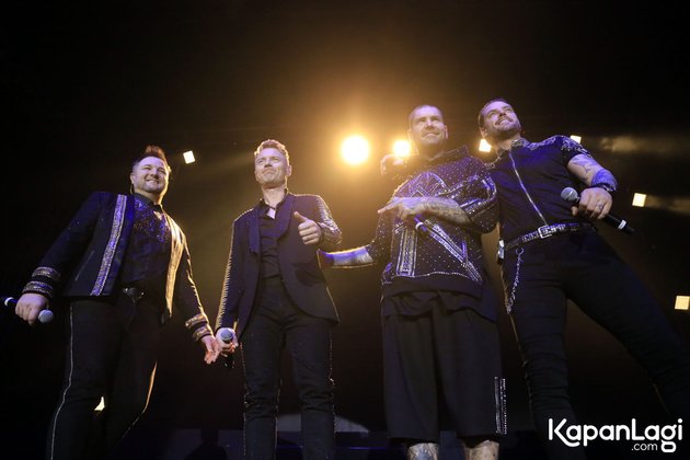 Keith Duffy, Mikey Graham, Ronan Keating dan Shane Lynch kompak mengenakan pakaian hitam di atas panggung.