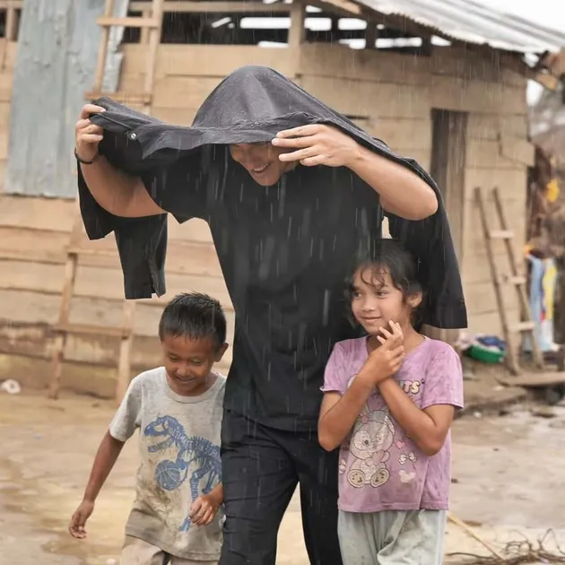 Hamish Daud melindungi anak kecil dari hujan.