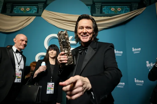 Jim Carrey tersenyum di depan kamera di Cesar Awards