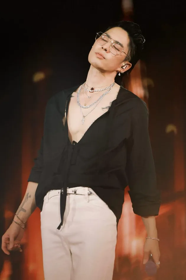 黒いトップスと白いパンツに眼鏡と重ね付けしたネックレスを合わせて歌うVanness Wu