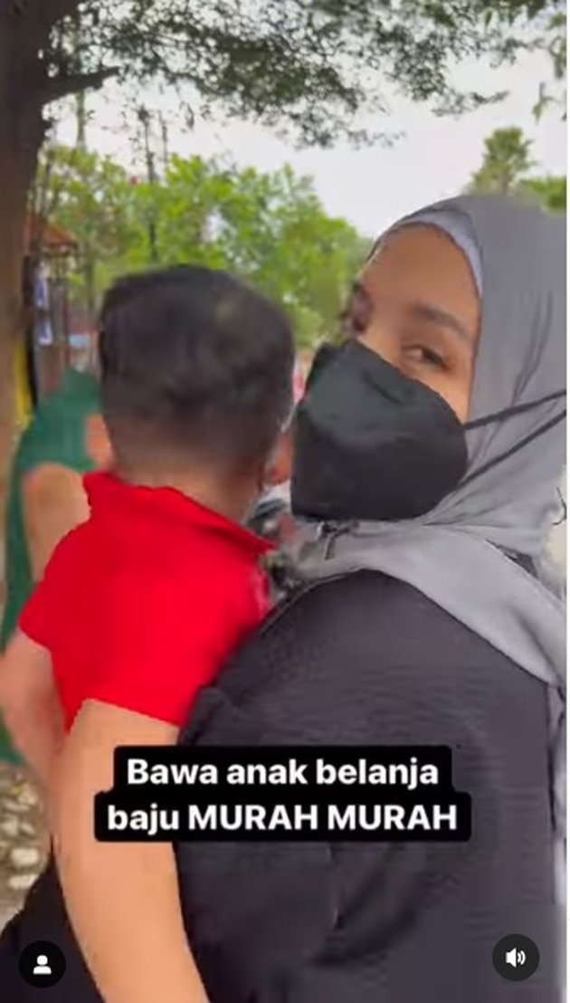 Dengan menggendong anak keduanya, Muhammad Kalundra Ratinggang, Tya Ariestya tampak berjalan menuju toko baju.