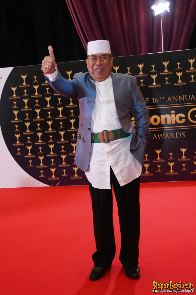 Latief Sitepu rapi mengenakan jas lengkap dengan peci putih dan sabuk khas Betawi.