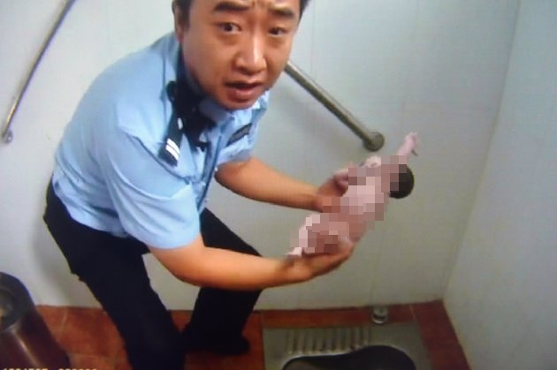 Petugas sedang mengambil bayi dari toilet | Photo: Copyright huffingtonpost.com