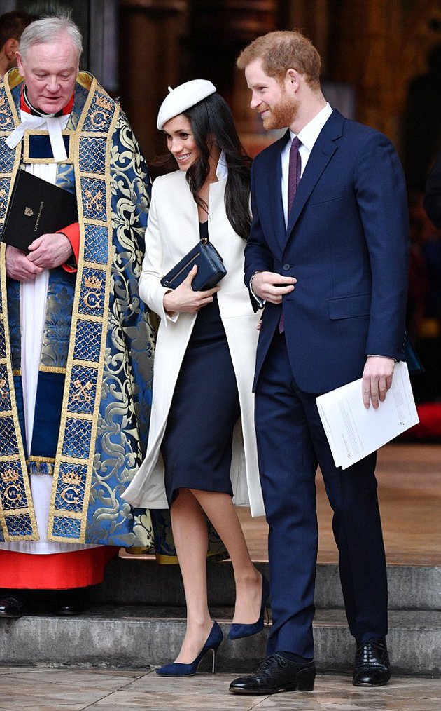 Sama halnya dengan sang Duchess of Cambridge, calon istri Pangeran Harry ini juga muncul dengan memakai dress berwarna navy. Meghan pun memberikan sentuhan manis lewat outer dan headpiece putih ini./copyright dailymail.co.uk/sry